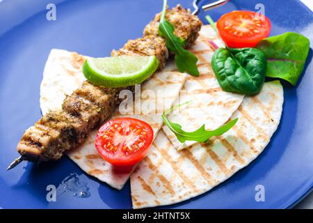 spiedino di carne alle erbe con pita pane, pomodori e lime Foto Stock