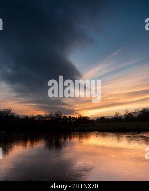 Tramonto sul cielo colorato su un lago ghiacciato. Bulwell Hall Park Nottingham Inghilterra Regno Unito Foto Stock