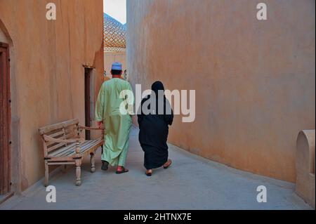 Coppia in tradizionale abbigliamento arabo sulla strada nella parte vecchia di Nizwa, Oman Foto Stock