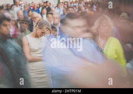 Folla di persone che camminano per la strada della città - immagine sfocata in movimento con volti irriconoscibili - giovane donna ferma, sentendosi giù, depresso Foto Stock