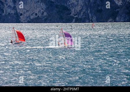 Piccole barche a vela navigano sul Lago di Garda in Italia Foto Stock