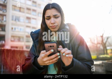 Giovane donna che esprime angoscia mentre legge la notizia della guerra in Ucraina Foto Stock