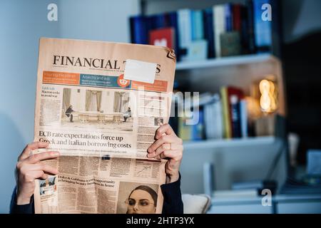 Parigi, Francia - 23 feb 2022: Donna che legge il giornale del Financial Times con il titolo di copertina discussione della tabella mentre Emmanuel Macron sta incontrando il presidente russo Vladimir Putin come cerca di evitare la guerra in Ucraina - gigantesco tavolo scintille scherza in tutto il mondo Foto Stock