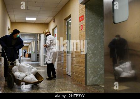 Kramatorsk, Ucraina, 1/3/2022, Un infermiere guarda i sacchi di sabbia che vengono trasportati per la protezione delle finestre in Kramatorsk City Hospital. Il presidente russo Vladimir Putin ha ordinato l'intervento militare il 24 febbraio, giorni dopo aver riconosciuto due enclavi separatisti nell'Ucraina orientale. Egli sosteneva che Mosca non aveva alcun piano per occupare il paese vicino, ma voleva “smilitarizzare” e “denazificare” l’Ucraina. Il presidente ucraino Volodymyr Zelenskyy ha accusato la Russia di cercare di installare un governo di burattini e ha detto che gli ucraini difenderanno il loro paese contro l'aggressione russa. Foto Stock