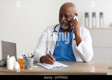 Ritratto di un medico sorridente che parla al telefono che lavora in clinica Foto Stock