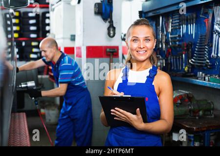 Ritratto di ragazza meccanica in tute con cartone con documenti in mano Foto Stock