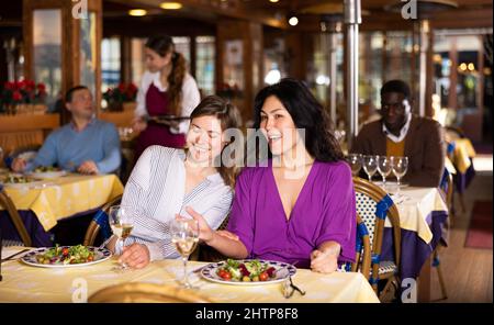 Incontro di due amiche felici a cena nel ristorante Foto Stock