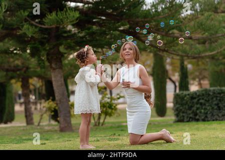 Madre e figlia soffiano bolle di sapone all'aperto. Foto Stock