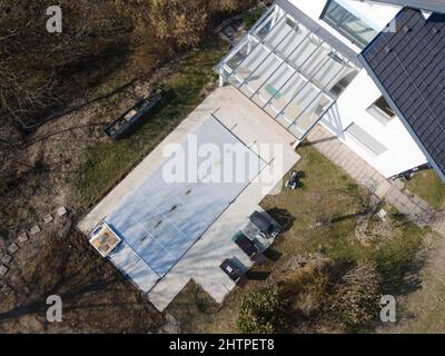 Drone volo su una piscina coperta con un tarp che è ancora in costruzione in un giardino Foto Stock