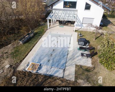 Drone volo su una piscina coperta con un tarp che è ancora in costruzione in un giardino Foto Stock