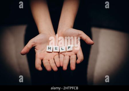 Ragazza che chiede aiuto. Ragazza allunga le mani con la parola aiuto nelle sue palme Foto Stock