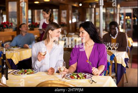 Incontro di due amiche felici a cena nel ristorante Foto Stock
