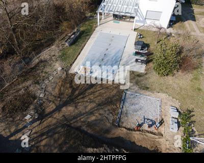 Drone volo su una piscina coperta con un tarp che è ancora in costruzione in un giardino Foto Stock