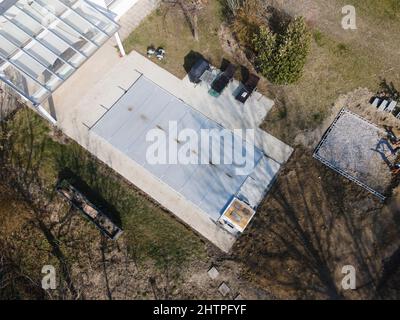Drone volo su una piscina coperta con un tarp che è ancora in costruzione in un giardino Foto Stock