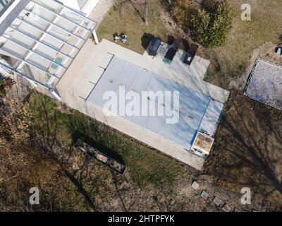 Drone volo su una piscina coperta con un tarp che è ancora in costruzione in un giardino Foto Stock