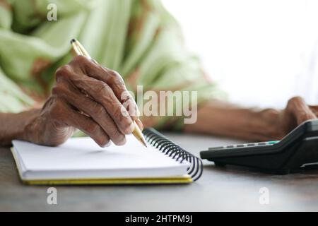 Primo piano di donne senior mano scrivere su blocco note. Foto Stock