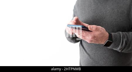 parte centrale dell'uomo che tiene lo smartphone in mano davanti alla parete bianca Foto Stock