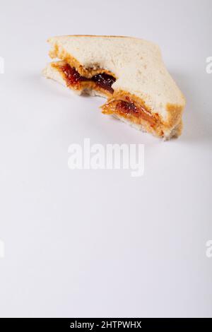 Primo piano del burro di arachidi e sandwich di gelatina con morso mancante su sfondo bianco con spazio copia Foto Stock