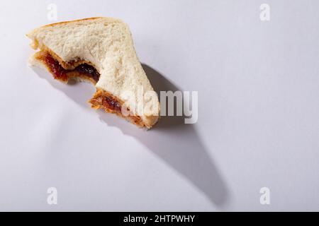 Vista ad angolo alto del burro di arachidi e sandwich di gelatina con morso mancante su sfondo bianco Foto Stock