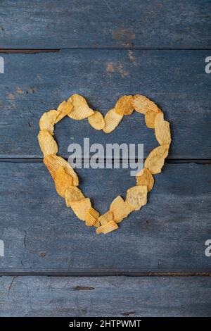 Vista dall'alto di patatine disposte a forma di cuore su un tavolo di legno Foto Stock