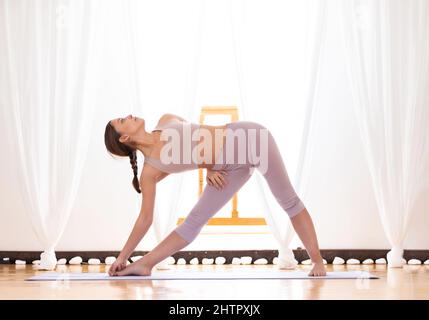 Giovane donna che fa TRIkonasana variante posa. Foto Stock