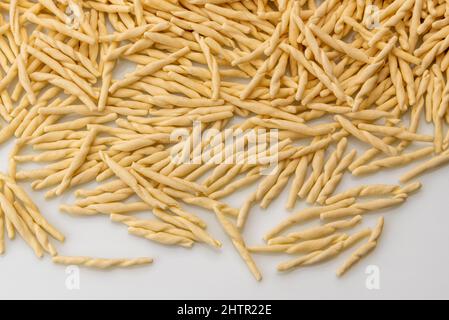 Trofie pasta cruda secca, tipica italiana ligure, da vicino su sfondo bianco Foto Stock