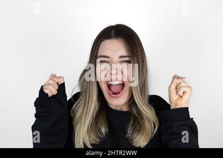 La ragazza ha entrambe le mani al suo fianco. Molto felice. Urla. Ha ricevuto buone notizie. Qualcosa che voleva si è avverata. Sembra che abbia vinto. Foto Stock