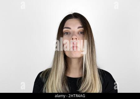 Primo piano ritratto interno di bella ragazza bruna giovane ragazza bella fredda. Donna che si fotola intorno, facendo pazzesco divertente grimace. Espressioni espressive del viso. Foto Stock