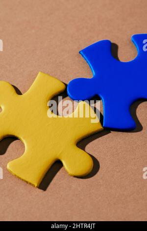 primo piano di due pezzi di puzzle, con i colori della bandiera ucraina, su sfondo marrone Foto Stock