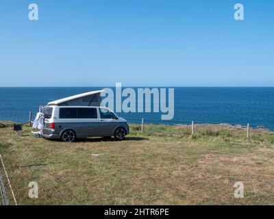 Un camper parcheggiato in cima a una scogliera a Porthcothan Bay Cornwall Regno Unito con vista sul mare in estate. Foto Stock