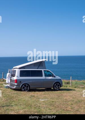 Un camper parcheggiato in cima a una scogliera a Porthcothan Bay Cornwall Regno Unito con vista sul mare in estate. Foto Stock