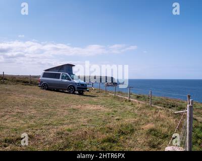 Un camper parcheggiato in cima a una scogliera a Porthcothan Bay Cornwall Regno Unito con vista sul mare in estate. Foto Stock