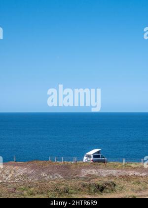 Un camper parcheggiato in cima a una scogliera a Porthcothan Bay Cornwall Regno Unito con vista sul mare in estate. Foto Stock