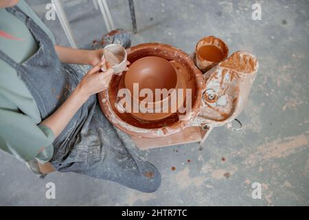 Mani di vasaio che fanno la ciotola di creta in officina di ceramica Foto Stock
