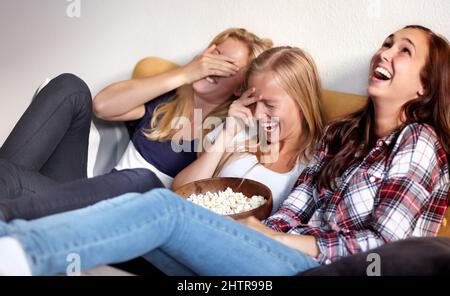 Questo è divertente. Girato di tre giovani amici godendo di una ciotola di popcorn mentre si guarda un film. Foto Stock