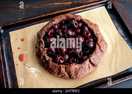 Torta di ciliegie al cioccolato crudo appena fatta: Torta di frutta cruda su una teglia rivestita in carta pergamena Foto Stock