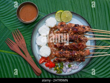 Cibo indonesiano famoso : Sate ayam (satay di pollo), servito con salsa di arachidi e torta di riso o lontong Foto Stock