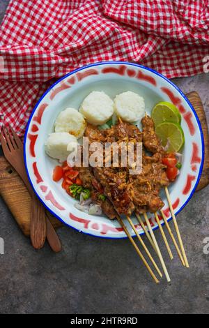 Cibo indonesiano famoso : Sate ayam (satay di pollo), servito con salsa di arachidi e torta di riso o lontong Foto Stock