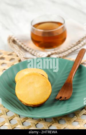 KUE Kuala Lumpur o Mud Cake, tradizionale torta indonesiana a base di patate, dolce e morbido. Servito su piatto in ceramica verde con tè Foto Stock