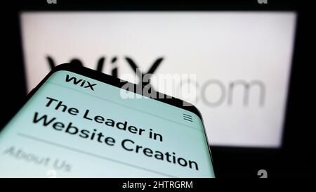 Telefono cellulare con pagina web della compagnia software israeliana Wix.com Ltd. Sullo schermo di fronte al logo aziendale. Mettere a fuoco sulla parte superiore sinistra del display del telefono. Foto Stock