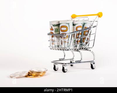 Bollette del dollaro a scorrimento in carrello e monete. Reddito e soldi spesi dallo shopping. Costi di consumo delle famiglie. Foto di alta qualità Foto Stock