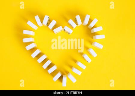 Chip Domino in forma cuore giallo background.Love per gioco da tavolo domino Foto Stock