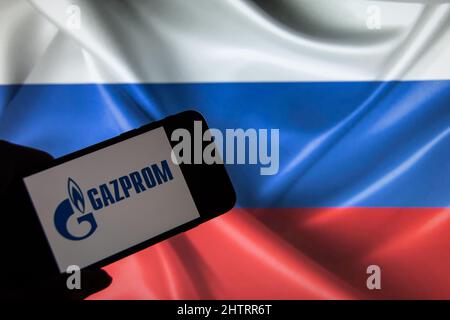 Rheinbach, Germania 2 marzo 2022, il logo del marchio 'Gazprom' su un display per smartphone davanti a una bandiera russa (in primo piano sul logo del marchio) Foto Stock