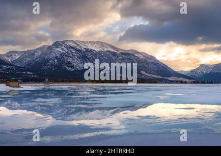 Sunrise Clouds riflette su un lago di montagna ghiacciato Foto Stock