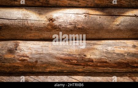 Parete di legno di tronchi meteorati orizzontali. Sfondo in legno texture con faretto. Foto Stock
