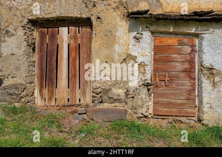 Due porte di legno di una casa colonica in rovina con pareti medievali. Foto Stock