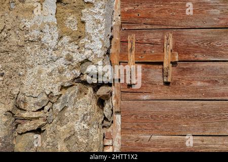 La serratura di legno di una porta di legno di una casa colonica in rovina con pareti medievali. Foto Stock