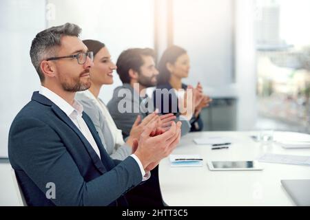 Celebrare un lavoro eccezionale. Scatto corto di un gruppo di uomini d'affari che si aggrappano le mani in un ufficio moderno. Foto Stock