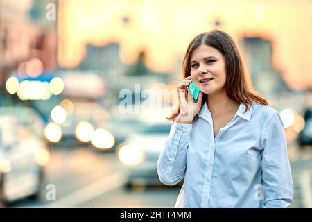 La donna chiama per un taxi sulla strada della città con traffico tramite smartphone. Foto Stock