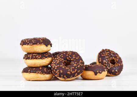 Ciambelle glassate al cioccolato con spolverini su sfondo bianco di legno con spazio per la copia Foto Stock